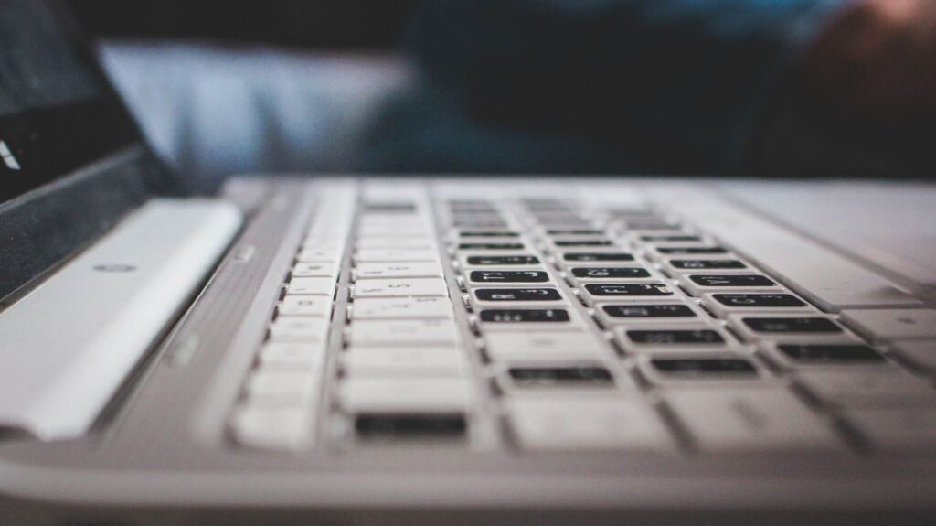 A laptop keyboard on a wooden desk, illustrating how to create a strong passphrase