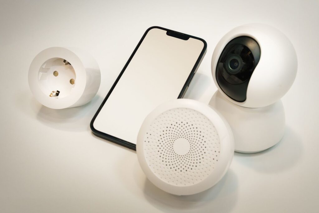 A smart home security camera, smart speaker, and phone on a table, showing how to secure smart home devices