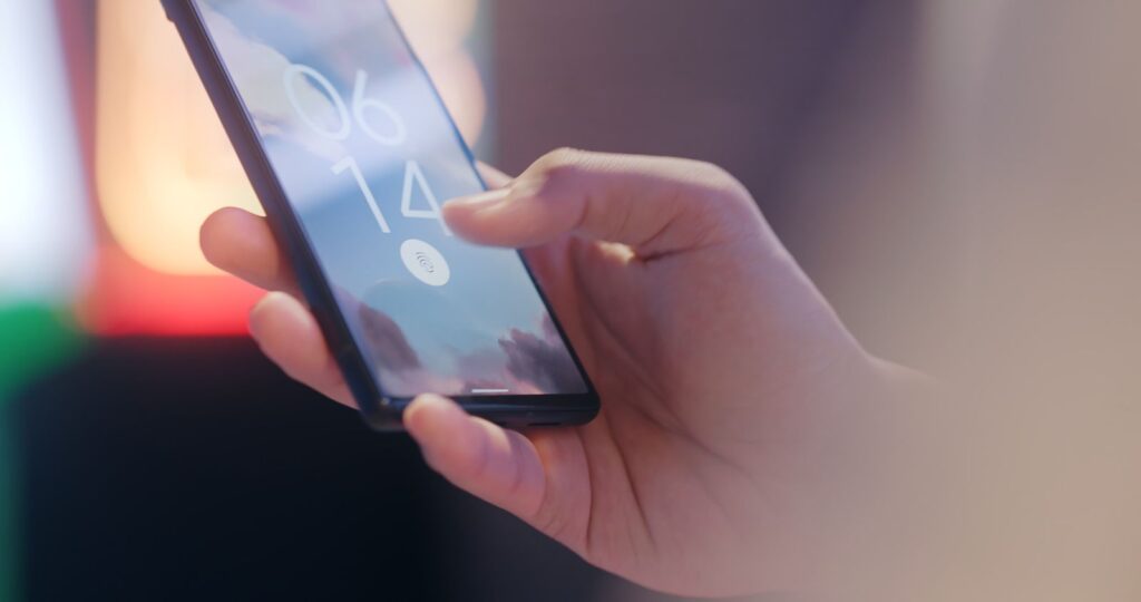 A hand using a fingerprint sensor to unlock a smartphone, illustrating passwordless passkey sign-in
